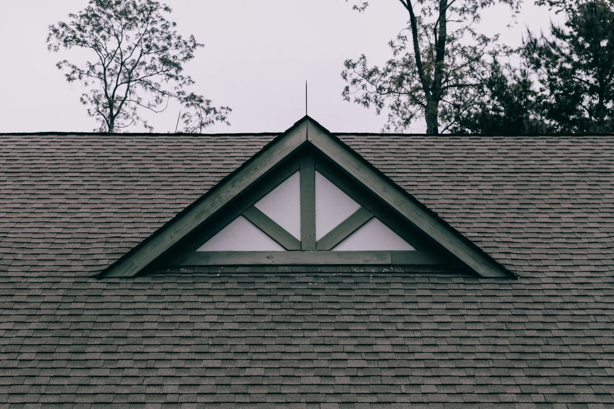 A brown asphalt shingle roof with a small wooden gable in the middle