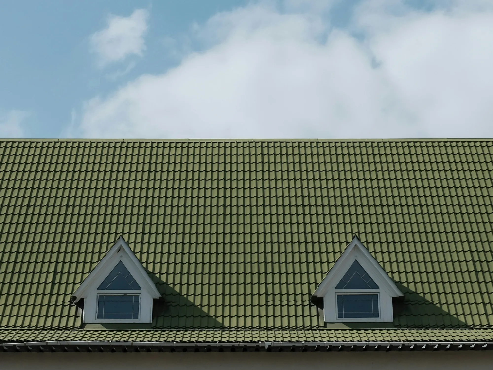 A green tile-style roof with two small dormer windows
